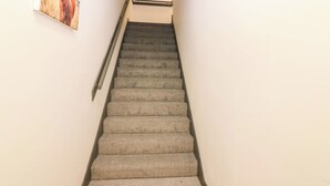 A carpeted staircase with a handrail, leading to a landing where a framed picture is displayed. - Apartment 1 (Aberdeen)
