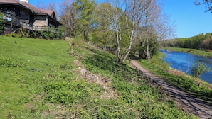 A riverside path with a stone house, trees, and a clear blue sky. - Apartment 1 (Aberdeen)