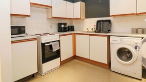 A compact kitchen with a microwave, stove, coffee maker, and washing machine. - Apartment 1 (Aberdeen)