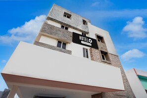 A modern hotel building with a sign reading 'HOTELO' and a company-serviced logo. - Deluxe Viswa Towers (Madurai)