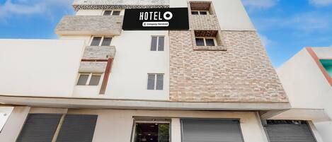 A hotel building with a sign reading 'HOTEL O' and a company-serviced logo.