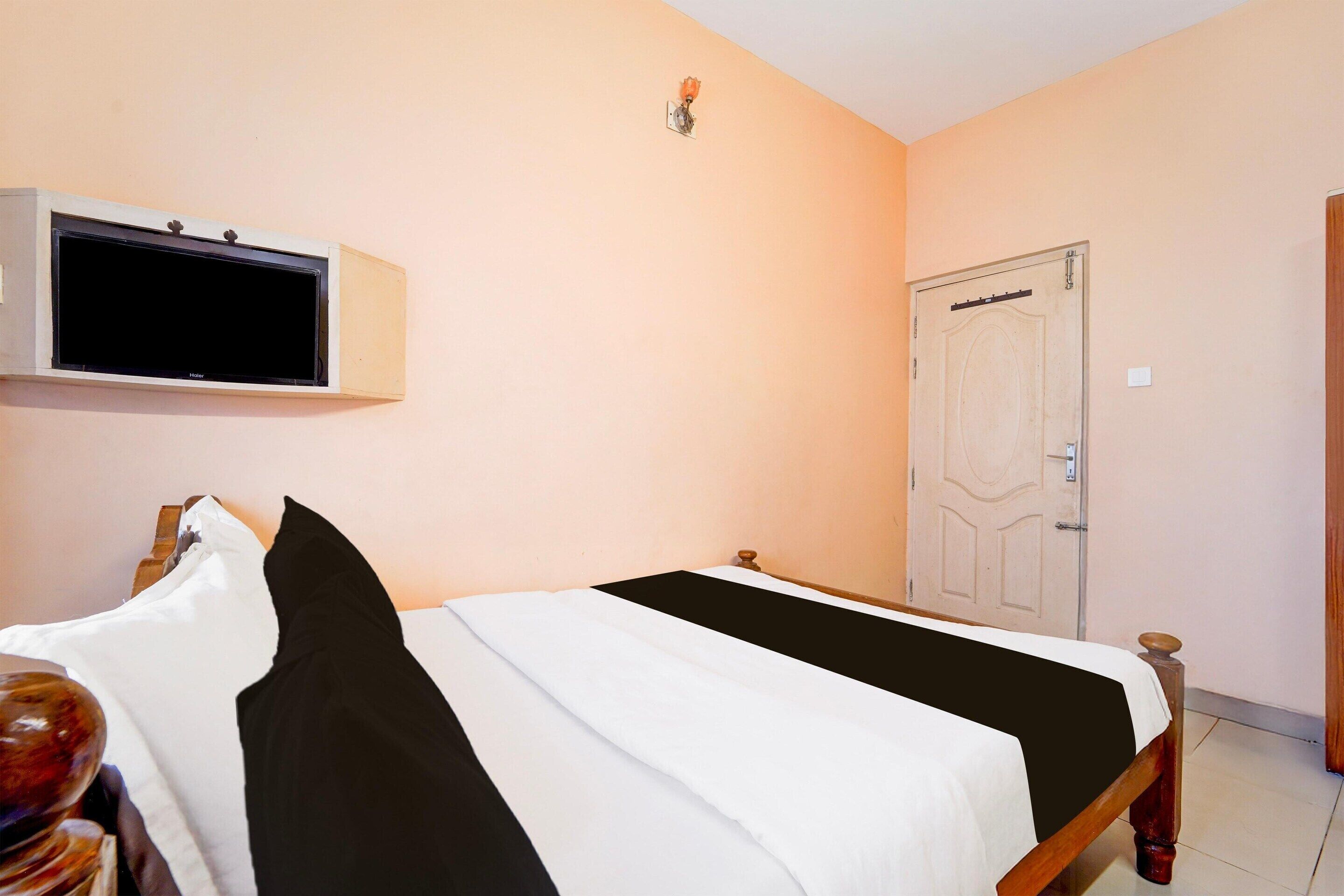 A bedroom with a bed, a television mounted on the wall, and a door.