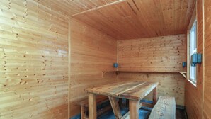 A wooden interior with a table and bench, a window, and a blue floor. - Home by the sea (Llandudno)