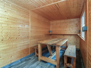 A wooden interior with a table and bench, a window, and a blue floor. - Home by the sea (Llandudno)