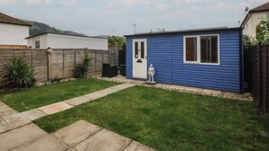 A residential backyard with a blue shed, a wooden fence, and a lawn. - Home by the sea (Llandudno)