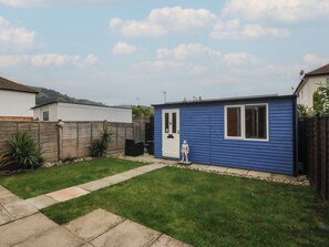A residential backyard with a blue shed, a wooden fence, and a lawn. - Home by the sea (Llandudno)