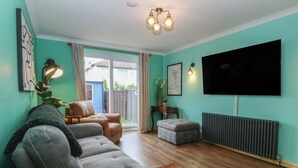A living room with a sofa, a coffee table, a TV, and a radiator. - Home by the sea (Llandudno)