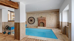 A swimming pool with a wooden deck, a brick fireplace, and a wheel. - Le Clos des Prés with Pool, Spa and Table Football (Rives de l'Yon)