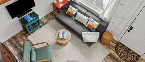 A cozy living room with a sofa, a coffee table, a TV, and a bookshelf.