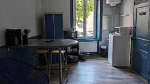 A compact kitchen with a dining area, a window with a view, and a refrigerator.