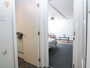 Un dormitorio con cama, una silla, una mesa y un radiador.