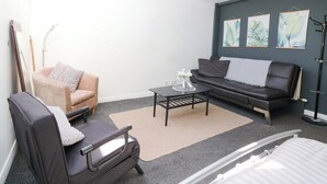 Ein modernes Wohnzimmer mit Sofa, Sessel, Couchtisch und einem Kunstwerk an der Wand.