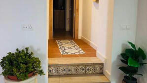A staircase with patterned tiles, a hanging light fixture, and a potted plant.