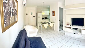 Una sala de estar con sofá, televisión y comedor con mesa y sillas.