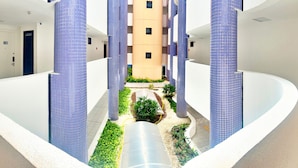 Un edificio moderno con un patio central, que incluye una fuente de agua y vegetación.