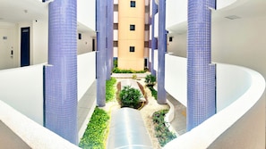Un bâtiment moderne doté d’une cour intérieure, agrémentée d’un élément aquatique et de verdure.