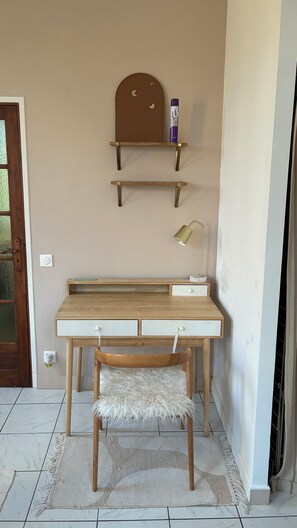 Ein Arbeitsbereich mit Schreibtisch, Stuhl, Regalen und einer Lampe.