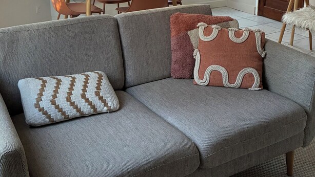 Un salon avec un canapé, une table à manger avec des chaises, une fenêtre avec des rideaux et une porte.