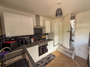 A modern kitchen with white cabinets, a black tiled backsplash, a gas stove, and a built-in oven. - The Signature Stay- 3 bed home, Premium Living, everytime (Cardiff)