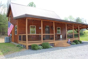 Une cabane en bois avec un porche, un drapeau américain et une pancarte indiquant « Résidence au bord du lac ».