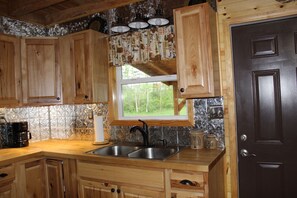 Une cuisine avec des meubles de rangement en bois, un évier à deux bacs, une fenêtre et une porte.