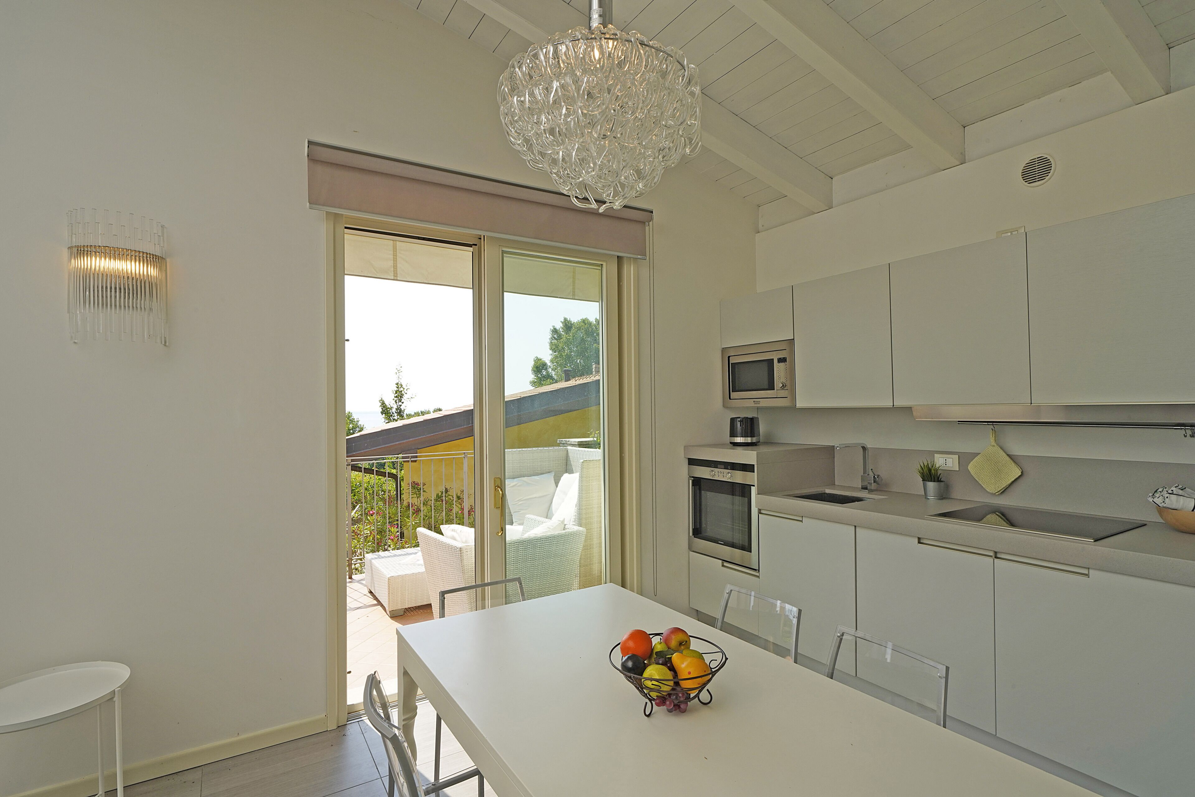A modern kitchen with a white countertop, a fruit bowl, and a hanging light fixture.