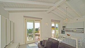 A modern living room with a sofa, a dining area, and a kitchen. - Montecolo Resort E7 by Wonderful Italy (Manerba del Garda)