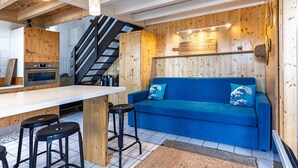 Una cucina moderna con elementi in legno, un divano blu con cuscini decorativi e una scala.