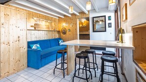 Una cucina moderna con elementi in legno, un divano blu e sgabelli da bar.