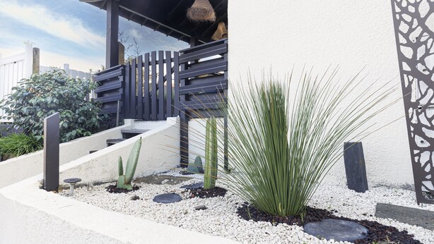 Zona esterna moderna con una scala in legno, una pianta di cactus e un pannello decorativo in metallo.