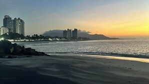 A beach with a cityscape in the background, including high-rise buildings and a mountain. - Coronado Luxury Club & Suites - 1 bedroom- Green fees for 2 & resort access (Panamá Oeste Province)