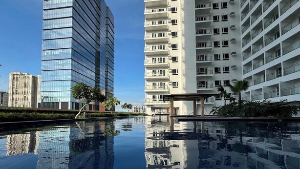 A modern building with a reflective pool in front. - Dyad Suites Pasay (Pasay)