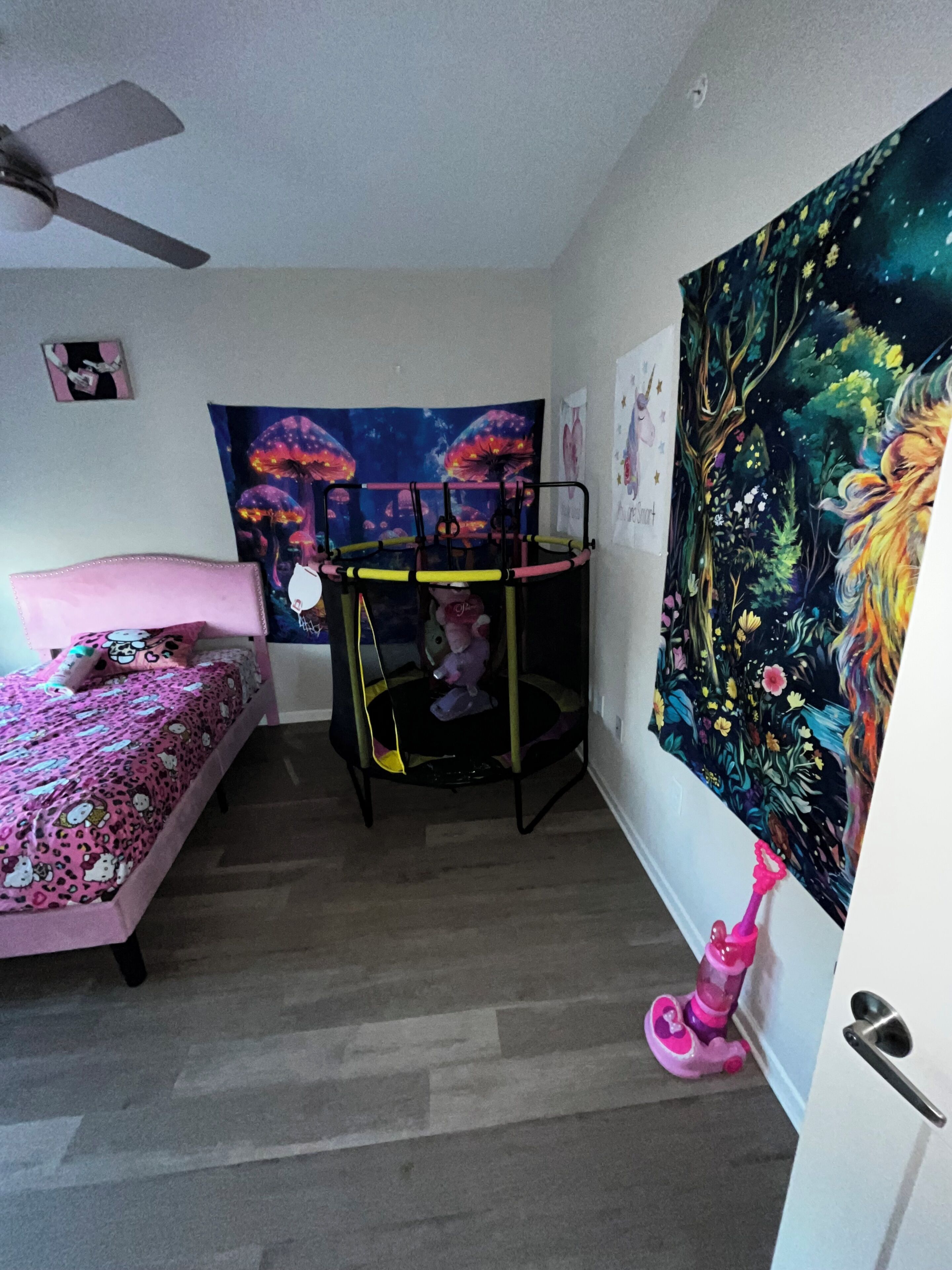 Ein Schlafzimmer mit Etagenbett, Deckenventilator, Wandteppich und einer Tür mit einem rosafarbenen Spielzeug.