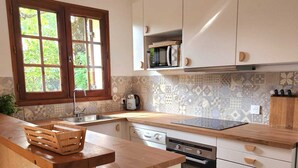 Een keuken met een houten aanrecht, een ingebouwde vaatwasser en een raam met uitzicht op groen.