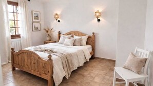 Een slaapkamer met een houten bed, een witte stoel en twee wandlampen.