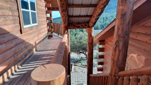 A wooden deck with a staircase leading to a covered area with a view of the surrounding landscape. - NEW Klondike Cabin, Saguache CO (Saguache)