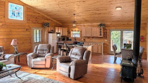 A log cabin interior with a living room, kitchen, and dining area, featuring wooden floors and a fireplace. - NEW Klondike Cabin, Saguache CO (Saguache)