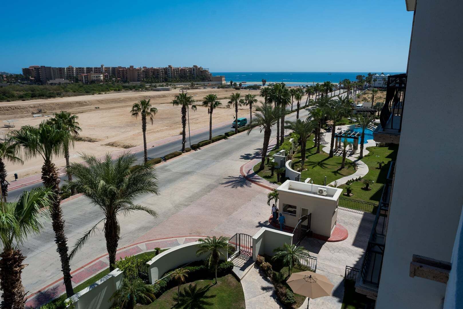 Een resort met een zwembad, palmbomen en uitzicht op het strand.