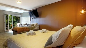 Una camera d'hotel con un letto, una TV a parete e un balcone con tavolo e sedie.