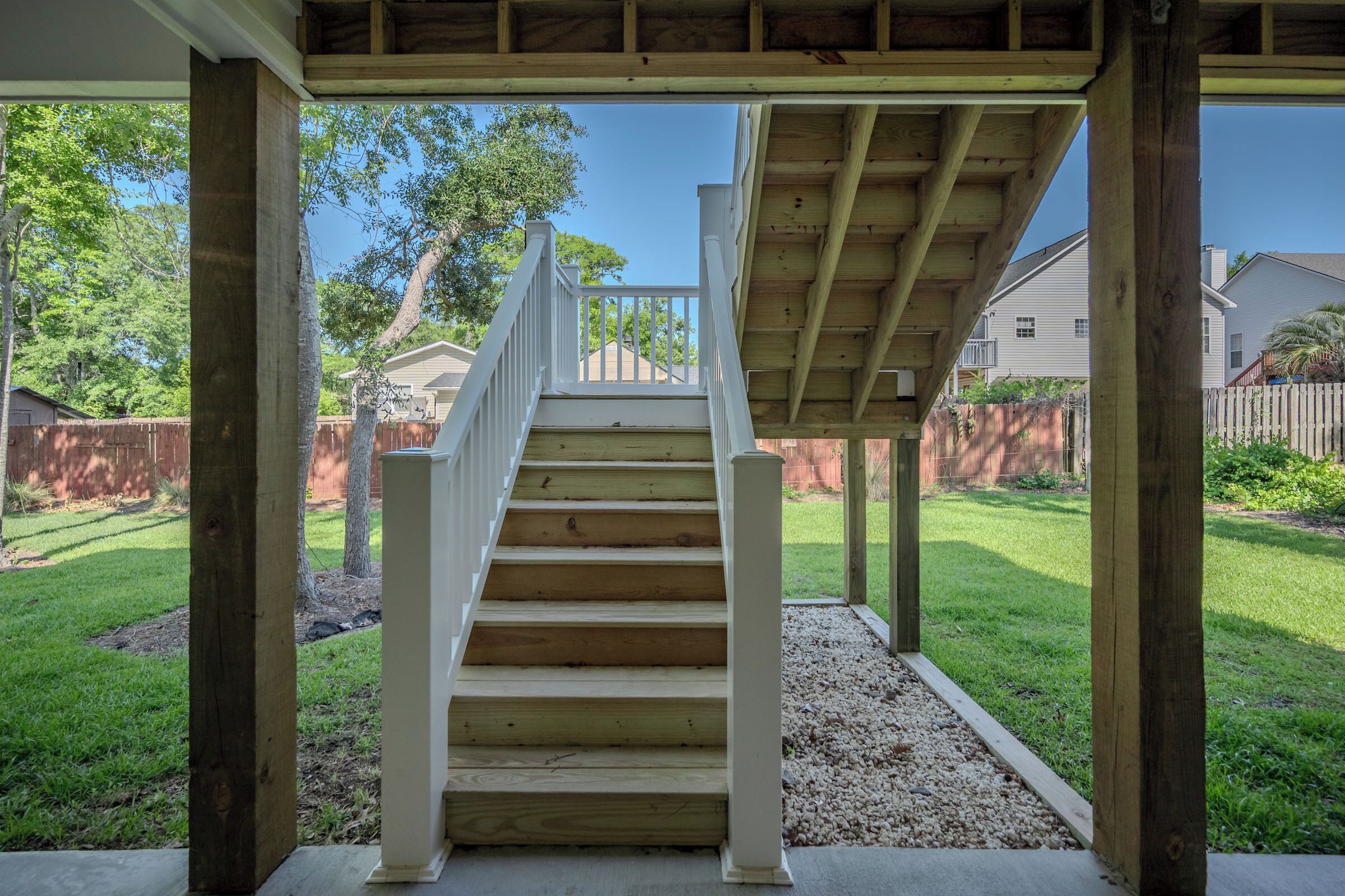 Una escalera de madera conduce a un espacio exterior cubierto con vistas a un barrio residencial.
