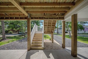 Ein überdachter Außenbereich mit Holzbalken, einem Betonboden und einer Treppe zu einer weißen Brüstung.