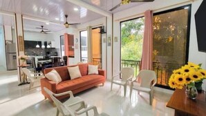 Ein modernes Wohnzimmer mit einer Couch, Sesseln, einem Esstisch und einem Balkon mit Blick.
