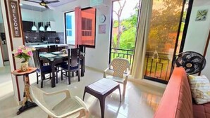 Ein modernes Wohnzimmer mit Essbereich, einer Couch, einem Ventilator und Blick ins Freie.