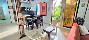 A modern living room with a dining area, a sofa, a fan, and a view of the outdoors.