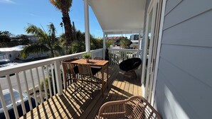 Een houten terras met een tafel, stoelen en een barbecue.