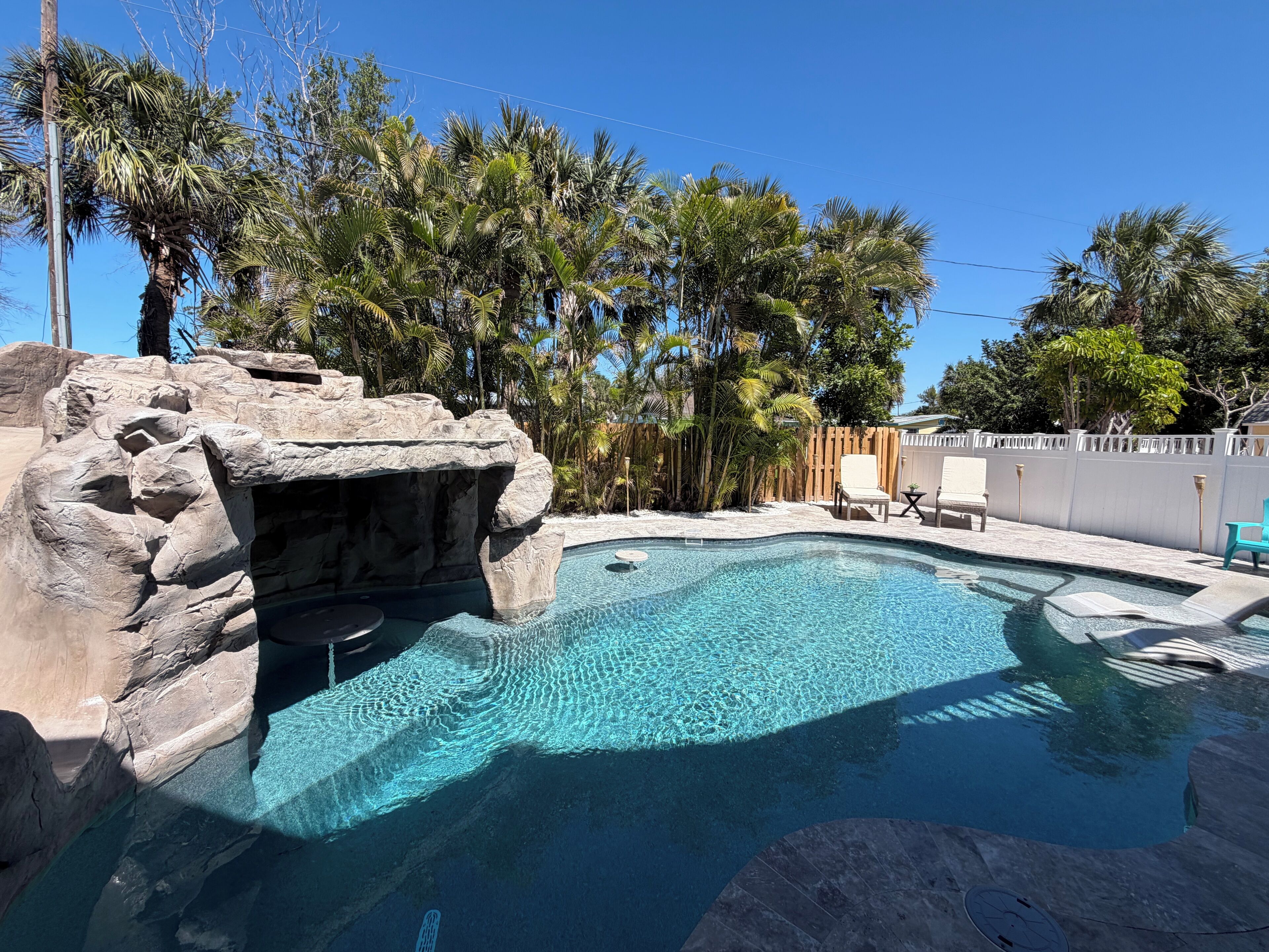 Ein Swimmingpool mit klarem Wasser, umgeben von Palmen und Felsen.