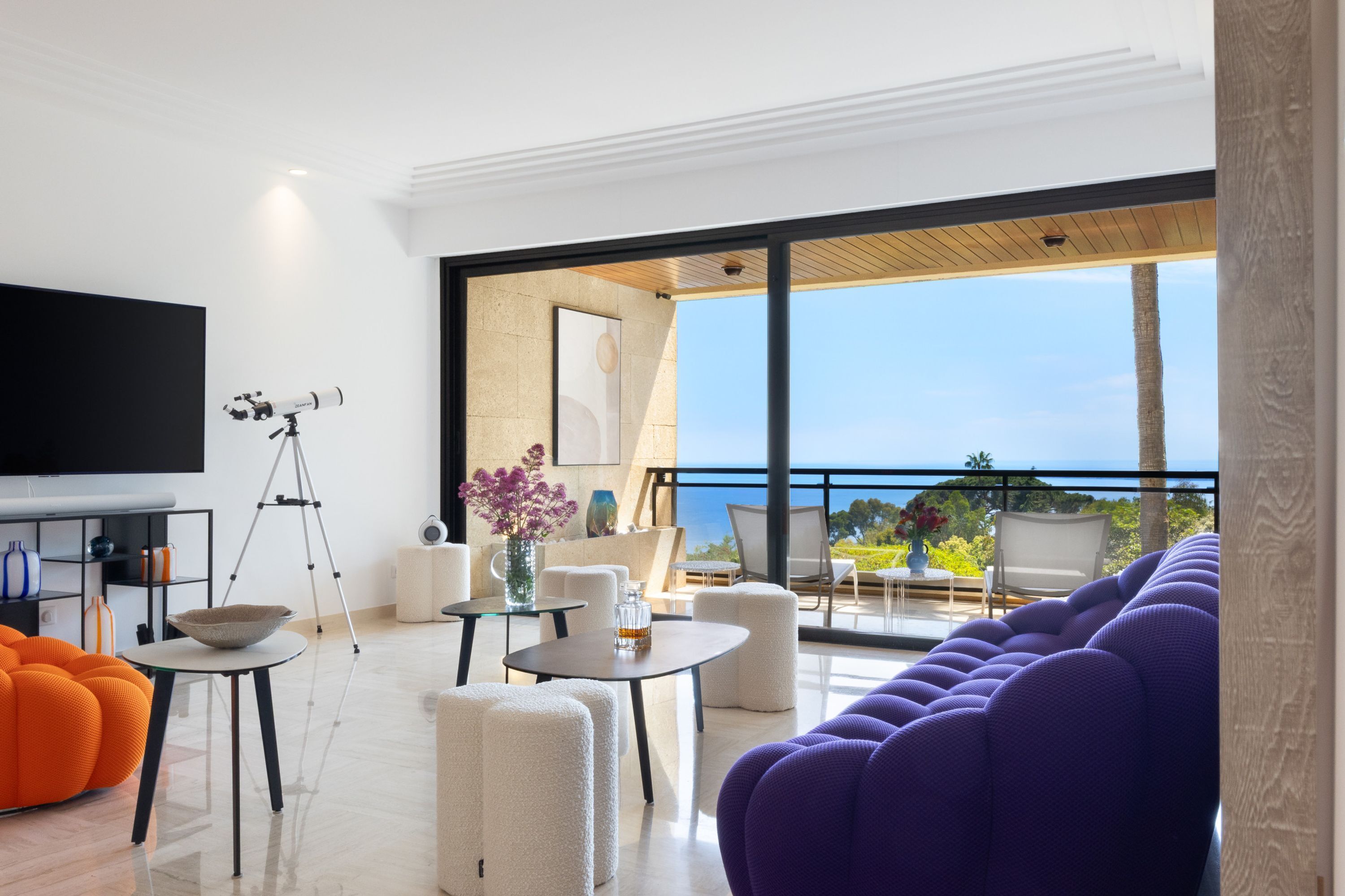 Un salon moderne doté d’un grand téléviseur, d’un télescope et d’un balcon offrant une vue imprenable.