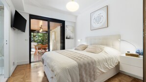 A bedroom with a bed, a nightstand, a TV, and a sliding glass door leading to a balcony. - 223 Le Gla Euls in Golfe Juan (Vallauris)