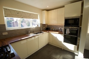 A modern kitchen with white cabinets, a built-in oven, and a window with a view of the outside. - Smart and Comfortable Cambridge House (Cambridge)