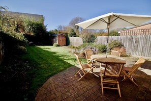 A patio with a table and chairs, a wooden fence, and a shed in a backyard. - Smart and Comfortable Cambridge House (Cambridge)